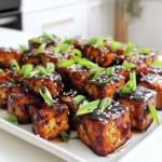 - 1 block (14 oz) firm tofu - 1/4 cup low-sodium soy sauce - 2 tablespoons pure maple syrup - 1 tablespoon rice vinegar To make crispy air fryer teriyaki tofu, start with firm tofu. It holds its shape well and gives a great texture. The low-sodium soy sauce adds umami flavor without too much salt. Pure maple syrup brings sweetness, balancing out the salty notes. Rice vinegar adds a little tang to the mix, enhancing the overall taste. - 1 tablespoon sesame oil - 2 cloves garlic, finely minced - 1 teaspoon fresh ginger, grated For flavor, sesame oil is key. It gives a nice nutty taste. Minced garlic and grated ginger add depth and freshness. Together, these ingredients create a rich and flavorful marinade that soaks into the tofu. - 2 teaspoons cornstarch - 2 green onions, finely chopped - A sprinkle of sesame seeds Cornstarch is crucial for that crispy outside. It coats the tofu, creating a crunchy texture when cooked. After air frying, garnish the tofu with chopped green onions and sesame seeds. This not only looks good but also adds extra flavor and crunch. Pressing the tofu: First, you need to press the tofu. This helps remove excess water. Wrap the tofu in a clean kitchen towel or paper towels. Place a heavy object on top. Let it sit for about 15 minutes. This step is key for a crispy outcome. Cutting into cubes: After pressing, cut the tofu into bite-sized cubes. Aim for uniform pieces. This ensures even cooking and helps each cube soak up the marinade well. Place the cubes in a large mixing bowl, ready for flavor. Combining soy sauce, maple syrup, and other ingredients: In a separate small bowl, whisk together the marinade. Use 1/4 cup of low-sodium soy sauce, 2 tablespoons of pure maple syrup, 1 tablespoon of rice vinegar, and 1 tablespoon of sesame oil. Add 2 minced garlic cloves and 1 teaspoon of grated ginger. Mix until it all blends into a smooth sauce. This marinade gives the tofu its rich flavor. Marinating: Pour the marinade over the cubed tofu. Toss gently so each piece gets coated. Let the tofu marinate for at least 20 minutes. Stir occasionally to ensure even flavor. This step is crucial for taste. Air frying process: After marination, sprinkle 2 teaspoons of cornstarch over the cubes. Toss gently again to coat each piece. Preheat your air fryer to 375°F (190°C) for about 5 minutes. Arrange the marinated tofu in the air fryer basket in a single layer. Leave space between the cubes for even cooking. Air fry for 15-20 minutes. Shake the basket halfway through. The tofu will turn golden brown and crispy. Enjoy your delicious meal! To get your tofu crispy, cornstarch is key. It creates a crunchy layer. After marinating, sprinkle cornstarch over the tofu cubes. Toss them gently to coat well. This step is crucial for that perfect crisp. Spacing in the air fryer also matters. Place the tofu cubes in a single layer. Leave space between each piece for air to flow. If your air fryer is small, cook in batches. This ensures even cooking and crispiness. You can spice up your teriyaki tofu with more flavors. Try adding spices like paprika, chili flakes, or garlic powder. Fresh herbs like cilantro or basil also work well. They can make your dish even more exciting. Before serving, drizzle some extra teriyaki sauce on top. You can also add a splash of sriracha for a spicy kick. This extra sauce enhances the taste and makes it look great. When it comes to serving, think about colorful accompaniments. Serve the tofu on a bed of rice, either white or brown. This not only looks nice but also adds heartiness. You can add steamed bok choy or vibrant stir-fried vegetables. This makes your meal more nutritious and colorful. Garnish with green onions and sesame seeds for a beautiful finish. This small touch makes a big difference in presentation. {{image_4}} If you want to switch things up, consider using different tofu types. - Silken tofu: This tofu is softer and works well in sauces but won't be crispy. - Extra-firm tofu: For a firmer bite, try extra-firm tofu. It holds its shape better. For gluten-free options, replace soy sauce with tamari. Tamari is a great gluten-free soy sauce. You can create fun teriyaki variations. - Honey teriyaki: Swap maple syrup for honey if you prefer sweetness. - Spicy teriyaki: Add a splash of sriracha for a kick. Adding veggies can enhance your dish. You can toss in bell peppers, broccoli, or snap peas. These add color and nutrition. If you don’t have an air fryer, you can still make crispy tofu. - Oven-baking: Preheat your oven to 400°F (200°C). Spread the marinated tofu on a baking sheet and bake for 25-30 minutes. Flip halfway for even crispiness. - Stovetop frying: Heat oil in a pan over medium heat. Fry the tofu until golden brown on all sides. This method gives a nice crunch, too. To keep your crispy air fryer teriyaki tofu fresh, follow these tips: - Store leftovers in an airtight container. - Refrigerate the tofu within two hours of cooking. - Use glass or BPA-free plastic containers for best results. Keeping tofu in a good container helps maintain its flavor and texture. Always let it cool down before sealing it up. When you want to enjoy your leftover tofu, the air fryer is the best choice. Here's how: - Preheat your air fryer to 375°F (190°C). - Place the tofu in the basket in a single layer. - Heat for about 5-10 minutes until it’s hot and crispy again. You can also reheat in a skillet. Just add a little oil and heat over medium heat until warm. This keeps the tofu crispy. You can freeze cooked tofu, but it may change texture. Here’s how: - Let the tofu cool completely. - Place it in a freezer-safe bag or container. - Remove as much air as possible before sealing. To freeze well, store it in small portions. When you're ready to eat, thaw it in the fridge overnight. Reheat in the air fryer for the best texture. To press tofu well, you need a few simple tools. A clean kitchen towel or paper towels works well. Wrap the tofu block tightly in your chosen towel. Then, place a heavy object on top, like a cast iron skillet or a few cans. Leave it for about 15 minutes. This helps to remove excess water, making your tofu crispier. For the best flavor, marinate your tofu for at least 20 minutes. This allows the tofu to soak up the teriyaki sauce. You can marinate it for up to 2 hours if you want a stronger flavor. Just be sure to stir it occasionally for even coating. Yes, you can use extra-firm tofu. It has a denser texture compared to firm tofu. This can give you an even crispier bite. However, extra-firm tofu may not absorb the marinade as well. If you like a firmer texture, go for it! In summary, we explored how to make crispy tofu in an air fryer. We discussed key ingredients like firm tofu, soy sauce, and flavor enhancers such as garlic and ginger. Step-by-step, I guided you through preparation, marination, and cooking. I shared tips for achieving crispiness and discussed various flavor profiles and cooking methods. Remember, tofu is versatile, so feel free to adapt the recipe to your taste. Enjoy experimenting with different ingredients and methods to make this dish your own!