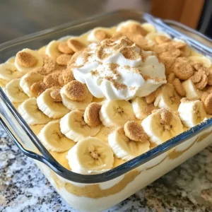Here’s what you will need for this delicious eggnog banana pudding: - 2 ripe bananas, sliced into rounds - 2 cups rich eggnog - 1/2 cup heavy cream - 1/4 cup granulated sugar - 1 teaspoon pure vanilla extract - 1/4 teaspoon ground nutmeg - 2 tablespoons cornstarch - 1/2 teaspoon salt - 1 package (14 oz) vanilla wafers - Whipped cream for topping These ingredients blend perfectly. The ripe bananas add a sweet touch. The eggnog gives a festive flavor, making this dessert special. The heavy cream creates a smooth texture, while the vanilla and nutmeg add warmth. Cornstarch helps thicken the pudding, giving it a nice body. I suggest using fresh bananas for the best taste. Look for ones that are ripe but not too soft. You can use any brand of eggnog you like, but choose a rich one for a creamy result. The vanilla wafers provide a crunchy layer, which contrasts nicely with the soft pudding. If you want to add a twist, consider using flavored eggnog or even a dairy-free version. You can also use different cookies instead of vanilla wafers. The key is to have ingredients you enjoy. This will make your eggnog banana pudding even more delightful. {{ingredient_image_2}} To start, grab a medium saucepan. Pour in the eggnog, and add the granulated sugar, ground nutmeg, and salt. Set the heat to medium. Stir the mixture gently until the sugar dissolves completely. Avoid letting it boil. This step creates a sweet and spiced base for your pudding. Next, you need to thicken the pudding. In a small bowl, mix cornstarch with a bit of the warm eggnog mixture. Whisk this until smooth. Then, slowly add this slurry back into the saucepan. Keep whisking over medium heat until it thickens and gently boils, which should take about 5-7 minutes. Once thickened, take it off the heat. This step makes the pudding rich and creamy. Now it's time for the whipped cream. In a separate bowl, whip the heavy cream with pure vanilla extract using an electric mixer. Continue until soft peaks form. This fluffy cream will lighten the eggnog mixture. Carefully fold in half of the whipped cream into the eggnog pudding. Then, fold in the rest until smooth. This gives your pudding a light and airy texture. Now, let's layer our dessert. Take a glass dish or individual cups. Start with a layer of vanilla wafers. Next, add a layer of sliced bananas, followed by a generous layer of eggnog pudding. Repeat these layers until all your ingredients are used. Make sure the final layer is pudding. This layering creates a beautiful and tasty dessert. Cover your assembled dessert with plastic wrap. Refrigerate for at least 3 hours. This time helps the flavors meld and sets the pudding perfectly. Right before serving, add a dollop of whipped cream on top of each serving. Finish with a light sprinkle of ground nutmeg for extra flavor. Enjoy this creamy and delightful treat! To get the right pudding consistency, focus on the thickening process. You want it creamy, not too runny. When you heat the eggnog, stir gently. This helps the sugar dissolve without boiling. A smooth blend is key. The technique of folding is crucial when adding whipped cream. Folding keeps the air in the cream, making the pudding light. If you stir, you lose that airy texture. So, fold gently until everything is combined. Serving this pudding in clear glass cups is a must. It shows off those beautiful layers of bananas, wafers, and pudding. You can also stack them in a trifle dish for a big gathering. For a fun touch, decorate each cup with banana slices and a swirl of whipped cream. A light sprinkle of nutmeg on top adds flavor and looks pretty. This will impress your guests and make it special. If you don't have ground nutmeg, you can use allspice or cinnamon instead. Both will give a warm taste to the pudding. Just remember to adjust the amount to match your taste. Nutmeg can be strong, so start with less. You can always add more later. This way, you can make the flavor just right for you. Pro Tips Use Ripe Bananas: Choose bananas that are spotty and slightly soft for the best flavor and sweetness in your pudding. Chill the Pudding: Allow the assembled pudding to chill for longer than 3 hours if possible; overnight chilling enhances the flavors even more. Homemade Whipped Cream: For a richer taste, whip your own heavy cream instead of using store-bought, and add a touch of powdered sugar for sweetness. Garnish Creatively: Enhance presentation by adding caramel drizzle or crushed nuts on top along with the whipped cream and nutmeg for added texture and flavor. {{image_4}} You can make Eggnog Banana Pudding even more fun. Try adding chocolate or caramel layers. This adds a rich taste that pairs well with bananas. Just drizzle chocolate syrup or caramel sauce between layers. You can also mix in spices like cinnamon or ginger. Just a pinch can elevate the flavor profile. These spices bring warmth and a hint of holiday cheer. If you need a gluten-free option, swap the vanilla wafers with gluten-free cookies. Many brands offer tasty alternatives that work well. For a dairy-free version, use coconut or almond milk eggnog. You can also whip coconut cream instead of heavy cream. These swaps keep the dessert creamy without dairy. You can serve this dessert in many ways. Individual servings in small cups look great. They make it easy for guests to enjoy. You can also use a large trifle dish for a family gathering. Mini dessert cups are perfect for parties, too. They offer a fun bite-sized option that guests love. To store leftovers, place the eggnog banana pudding in an airtight container. This keeps it fresh and tasty. You should consume it within 3 to 4 days. The flavors improve as it sits, but don’t wait too long! Yes, you can freeze eggnog banana pudding! To freeze, cover it tightly with plastic wrap and then aluminum foil. This prevents freezer burn. It’s best to freeze it for up to 1 month. When you want to eat it, thaw the pudding in the fridge overnight. Avoid microwaving, as this can change the texture. After thawing, stir gently to bring back its creamy goodness. Enjoy the delightful treat! If you do not have eggnog, you can use milk or cream mixed with spices. A mix of whole milk, sugar, and a pinch of nutmeg works well. For a festive twist, try adding a splash of vanilla extract and a bit of cinnamon. You can also use store-bought non-dairy eggnog for a vegan option. This will keep the creaminess while allowing you to enjoy the flavors. This dessert can last in the fridge for about 3-4 days. Store it in an airtight container to keep it fresh. If you see any changes in texture or smell, it is best to discard it. Always check your dessert before serving, just to be safe! Yes, you can make this dessert a day in advance. This will let the flavors blend well together. Just store it in the fridge after assembling. The pudding will set nicely. However, the bananas may brown slightly, so you might want to add them just before serving. This keeps them fresh and bright. This dessert combines simple ingredients to create a tasty treat. You learned how to layer bananas, vanilla wafers, and a creamy eggnog pudding. Don't forget the whipped cream and nutmeg for that final touch. Experimenting with flavors and variations can make it your own. Storing leftovers is easy if you follow the guidelines. I hope you try this recipe soon and enjoy every bite!